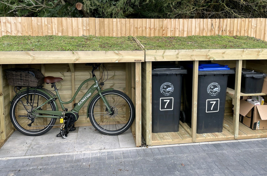 Bike shelter storage next to a store for wheelie bins and recycling bin boxes, with a living green roof planter full of sedum plants 
